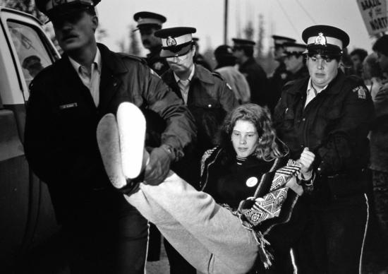 An arrest at the Kennedy River Bridge in 1993. Typically the protestors would  lie on the road, offering no resistance as the RCMP carried them away.